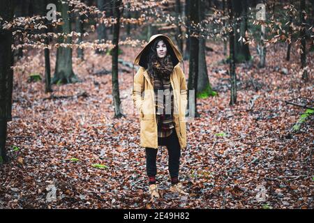 femme naturellement forte avec manteau d'hiver et écharpe tient dedans bois d'or Banque D'Images