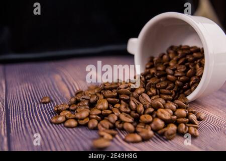 Un grain de café arrosé d'une tasse blanche sur un table en bois Banque D'Images