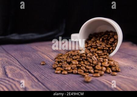 Un grain de café arrosé d'une tasse blanche sur un table en bois Banque D'Images