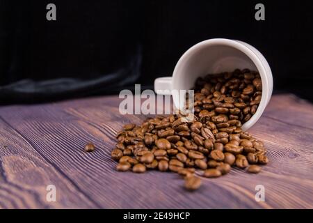 Un grain de café arrosé d'une tasse blanche sur un table en bois Banque D'Images