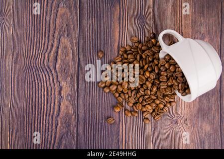 Un grain de café arrosé d'une tasse blanche sur un table en bois Banque D'Images