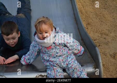 Amusement au parc - frère et sœur jouant dessus The Slide - frères et sœurs jouant - amis - Royaume-Uni Banque D'Images