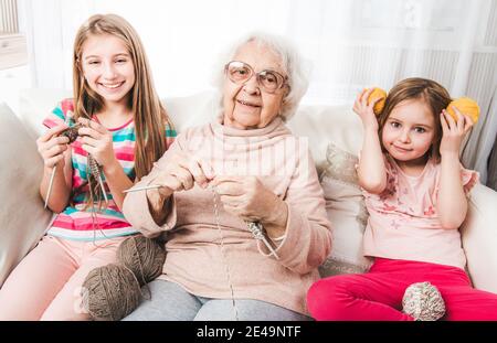 Petites-filles souriantes avec grand-mère tricoter ensemble Banque D'Images