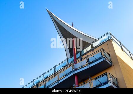 Bâtiment moderne avec balcons et une extraordinaire structure de toit sous la forme d'une voile soutenue par un pilier. Banque D'Images