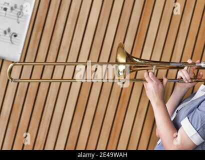 Photo rognée d'une jeune fille jouant au trombone dans la classe musicale Banque D'Images