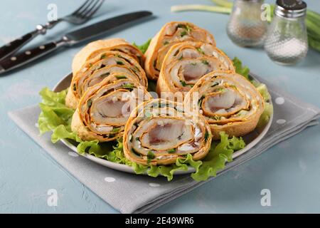 Rouleau de lavash avec hareng, pommes de terre et oignons sur fond bleu clair. Banque D'Images