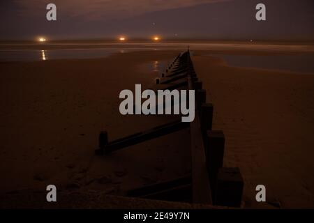 Défense de plage la nuit avec feux de bateau à l'horizon Banque D'Images