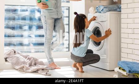 Une jeune femme au foyer et une petite fille font le linge ensemble Banque D'Images