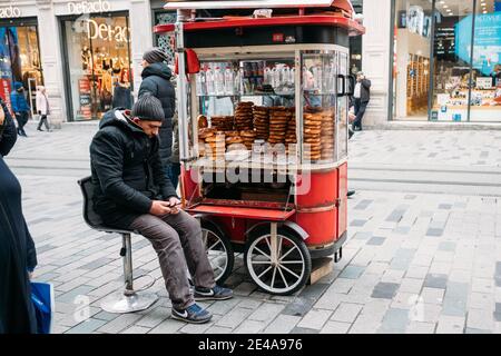 TURQUIE, ISTANBUL, 14 DÉCEMBRE 2018: Vendeur et chariot avec bagels nationaux turcs Simits sur la rue Istiklal. Banque D'Images