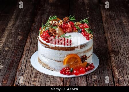 Délicieux gâteau sucré décoré de fruits et de romarin, placé sur une table rustique ancienne. Banque D'Images