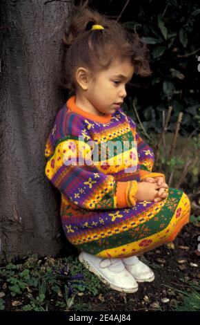 petite fille malheureuse assise sous l'arbre Banque D'Images