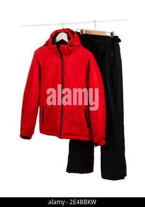 Veste de ski rouge imperméable et coupe-vent et pantalon noir sur cintres isolés sur fond blanc. Banque D'Images