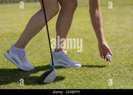 Bas section de la femme caucasienne jouant au golf se penchant à la place balle avant de prendre le cliché Banque D'Images