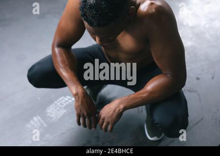 Homme afro-américain portant des vêtements de sport qui s'accroupissement après avoir lutté cordes dans le bu urbain vide Banque D'Images