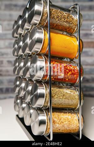 Un porte-épices en métal avec de nombreuses bouteilles de verre remplies de différentes épices, prise studio Banque D'Images