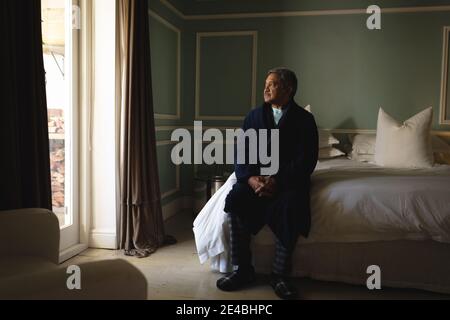 Homme afro-américain senior assis sur un lit dans un chambre Banque D'Images