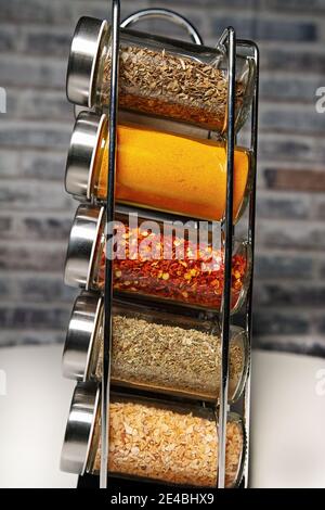 Un porte-épices en métal avec de nombreuses bouteilles de verre remplies de différentes épices, prise studio Banque D'Images