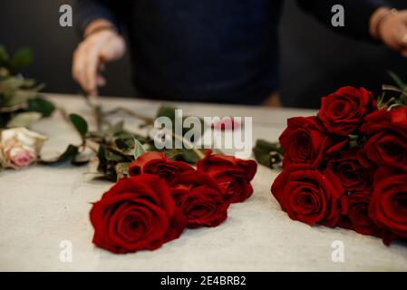 Fleuriste caucasien vendant des bouquets de roses rouges et roses pour la Saint-Valentin. Concept des émotions humaines, de l'expression faciale, de l'amour et du travail acharné Banque D'Images