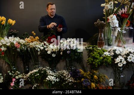 Fleuriste caucasien vendant des bouquets de roses rouges et roses pour la Saint-Valentin. Concept des émotions humaines, de l'expression faciale, de l'amour et du travail acharné Banque D'Images