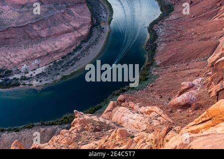 Un bateau sur le fleuve Colorado qui semble minuscule par rapport à ses environs vient dans le célèbre Horseshoe Bend de Glen Canyon en Arizona. Banque D'Images