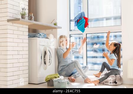 Une jeune femme au foyer et une petite fille font le linge ensemble Banque D'Images