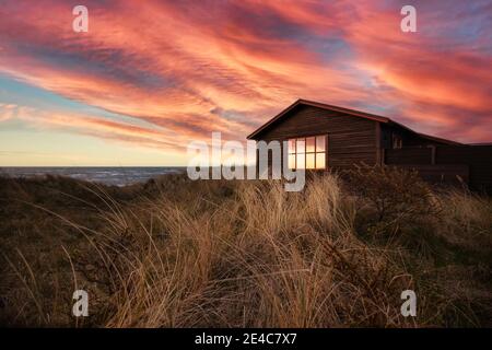 Maison dans les dunes au coucher du soleil sur une plage près de Hirtshals. Banque D'Images