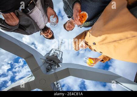 Jeunes, loisirs dans la ville. Trois personnes se tiennent au port avec un verre à la main. Vue du groupe du point de vue d'une grenouille Banque D'Images