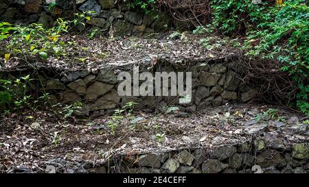 Murs en terrasse en pierres enchâssés dans des filets en treillis métallique (gabions). Banque D'Images