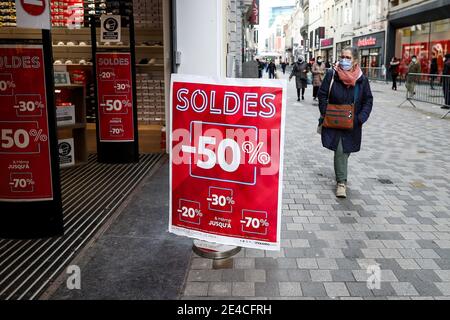 Bruxelles, Belgique. 22 janvier 2021. Une femme portant un masque passe devant un magasin avec des affiches de vente à Bruxelles, Belgique, le 22 janvier 2021. Les ventes annuelles d'hiver en Belgique ont débuté le 4 janvier. Pour stimuler la consommation, les ventes d'hiver de quatre semaines prévues ont été prolongées de deux semaines jusqu'au 15 février. Credit: Zhang Cheng/Xinhua/Alay Live News Banque D'Images