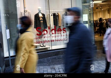 Bruxelles, Belgique. 22 janvier 2021. Des personnes portant des masques de visage marchent devant une boutique avec des affiches de vente à Bruxelles, Belgique, le 22 janvier 2021. Les ventes annuelles d'hiver en Belgique ont débuté le 4 janvier. Pour stimuler la consommation, les ventes d'hiver de quatre semaines prévues ont été prolongées de deux semaines jusqu'au 15 février. Credit: Zhang Cheng/Xinhua/Alay Live News Banque D'Images