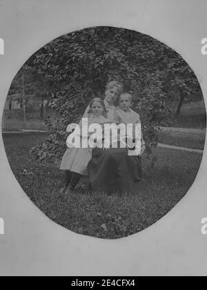 Archive américaine portrait monochrome d'une femme assise dans un jardin avec deux enfants, un garçon et une fille. Prise à la fin du XIXe siècle à Port Byron, NY, États-Unis Banque D'Images