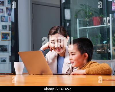 Les parents et les enfants regardent les ordinateurs portables souriant sans regarder le objectif Banque D'Images