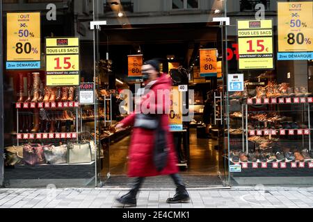 Bruxelles, Belgique. 22 janvier 2021. Une femme portant un masque passe devant un magasin avec des affiches de vente à Bruxelles, Belgique, le 22 janvier 2021. Les ventes annuelles d'hiver en Belgique ont débuté le 4 janvier. Pour stimuler la consommation, les ventes d'hiver de quatre semaines prévues ont été prolongées de deux semaines jusqu'au 15 février. Credit: Zhang Cheng/Xinhua/Alay Live News Banque D'Images