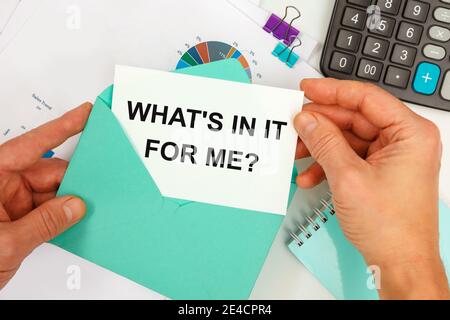 L'homme d'affaires sort une carte de l'enveloppe avec le texte CE QUI EST DANS ELLE POUR MOI, sur le fond du bureau. Banque D'Images