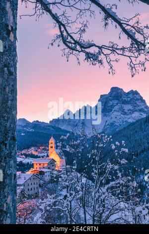 Italie, Vénétie, Belluno, Agordino, village alpin de Colle Santa Lucia en hiver à l'aube, maisons illuminées et église, Dolomites Banque D'Images