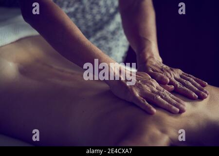 Gros plan des mains d'une masseuse professionnelle sur le dos d'une femme recevant un massage corporel intégral. Banque D'Images
