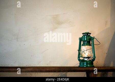 Lampe au kérosène lanterne à l'huile brûlante à la lumière douce et lumineuse sur un banc en bois. Banque D'Images