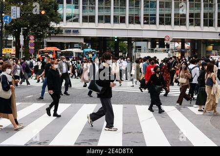 Les gens qui utilisent le passage à la broutte en face de la gare de Shibuya. Ils portent des masques faciaux lors de l'éclosion de coronavirus. Un flou de mouvement. (10/2020) Banque D'Images