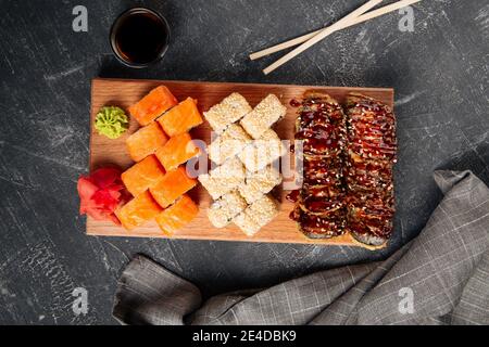 Vue de dessus sur un assortiment de petits pains à sushis sur une planche de bois avec de la sauce au wasabi et au soja Banque D'Images