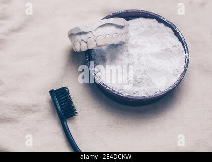 Poudre blanche bio de dent de dentifrice dans un pot rond avec une brosse en bambou noir et moule de mâchoire, hygiène dentaire et de soin dentaire de blanchiment des dents concept Banque D'Images