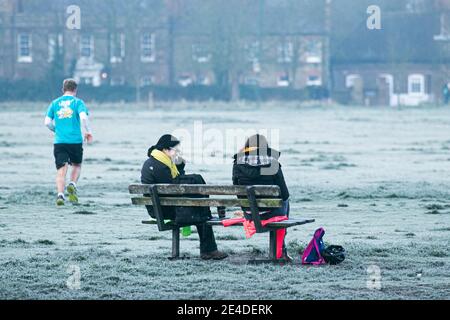 WIMBLEDON LONDRES, ROYAUME-UNI 23 JANVIER 2021. Deux femmes assises sur un banc sur un paysage gelé et couvert à Wimbledon Common le matin d'un froid glacial. De nombreuses régions du Royaume-Uni connaissent des inondations causées par de fortes pluies de la tempête Christoph. Credit: amer ghazzal / Alamy Live News Banque D'Images