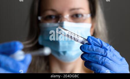 Test COVID-19 dans les mains du médecin de près, la femme en masque médical veut prendre des échantillons de salive et de nez pour le test PCR du coronavirus. Concept de corona vi Banque D'Images
