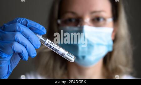 Tube à essai pour PCR COVID-19 dans la main du médecin, la femme dans le masque médical tient le kit de prélèvement de l'écouvillon du coronavirus en laboratoire. Concept de diagnostic du virus corona, téstine Banque D'Images