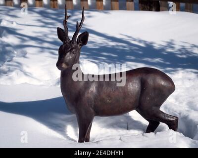 Sculpture horizontale de chevreuil en bronze debout dans la neige. Banque D'Images