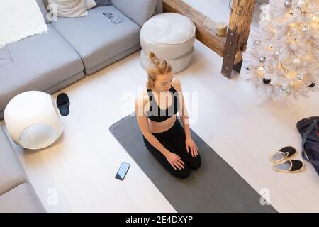 Belle femme blonde faisant l'entraînement à la maison à l'intérieur. Femme pratiquant le yoga à la maison. FIT Girl en utilisant des tutoriels d'entraînement pour un style de vie actif sain. Femme Banque D'Images