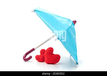 Paire de coeurs rouges tricotés sous un parapluie. Assurance vie ou santé, amour. Le concept d'importance de la famille et de la maison Banque D'Images