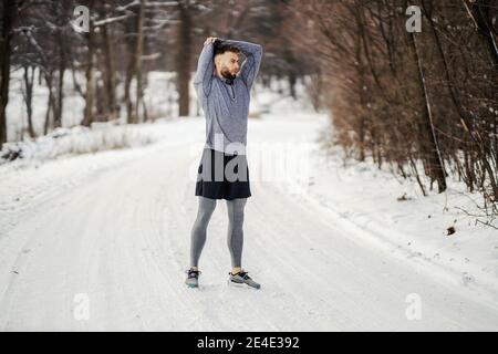 Faites des exercices d'étirement et d'échauffement en vous tenant sur un sentier enneigé en forêt en hiver. Une vie saine, une forme physique en hiver, le temps froid Banque D'Images