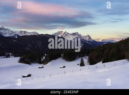 Magnifique lever de soleil dans les montagnes avec des cabanes couvertes de neige Premier plan - Alpes avec Alpspitze et Zugspitze en arrière-plan Banque D'Images