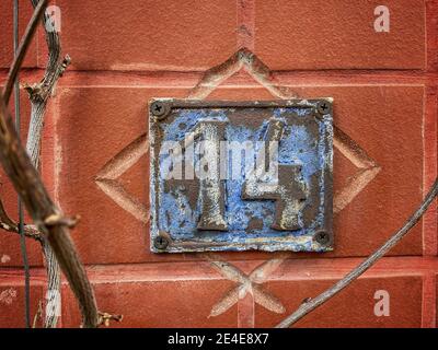 Numéro 14, le nombre de maisons, appartements, rues. Le numéro blanc sur une plaque métallique bleue, le numéro de maison quatorze (14) sur un mur rugueux. Banque D'Images