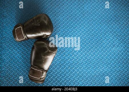 gants de boxe noirs sur sol en fer bleu au camp de boxe Banque D'Images